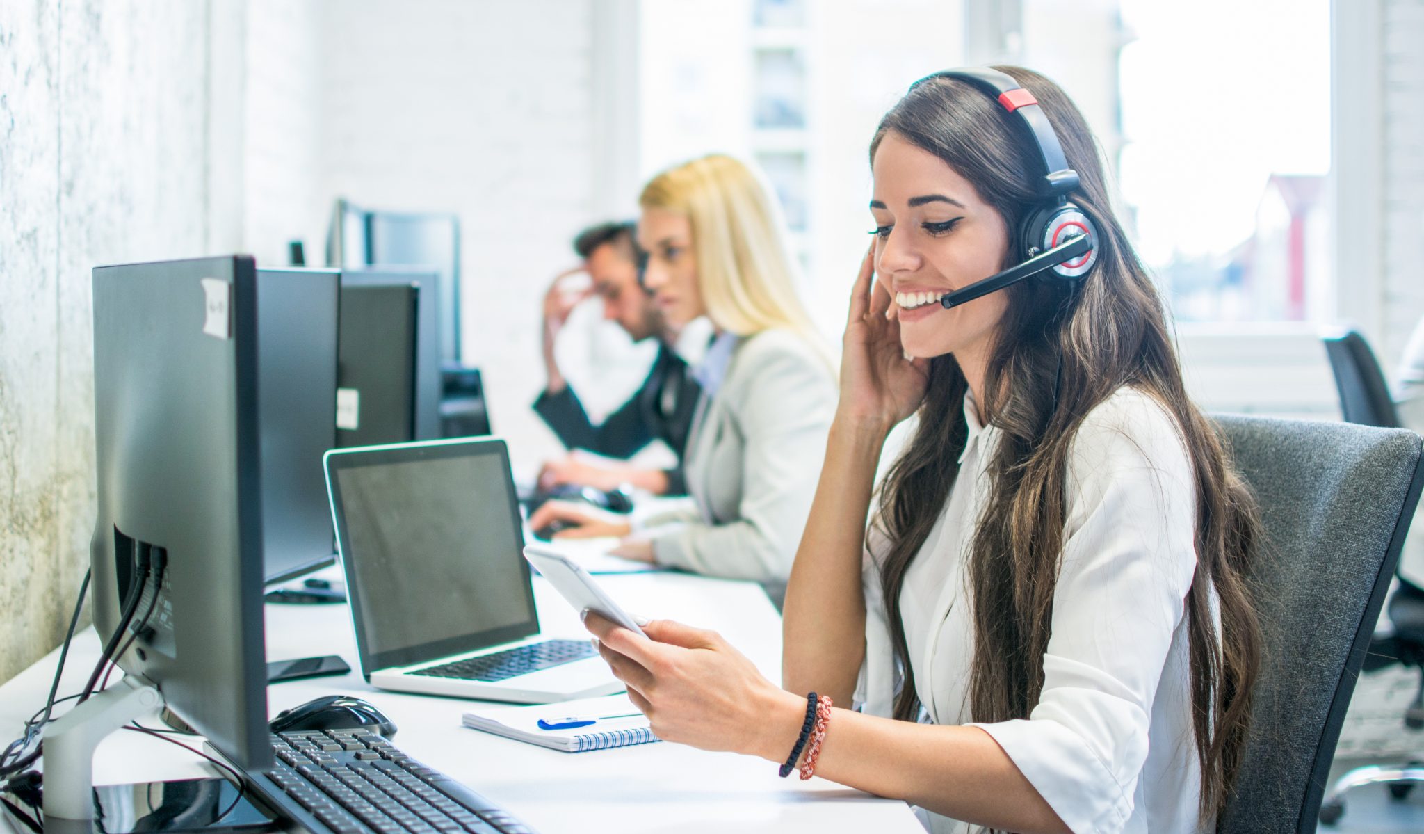 Friendly female customer support operator with headset using pho